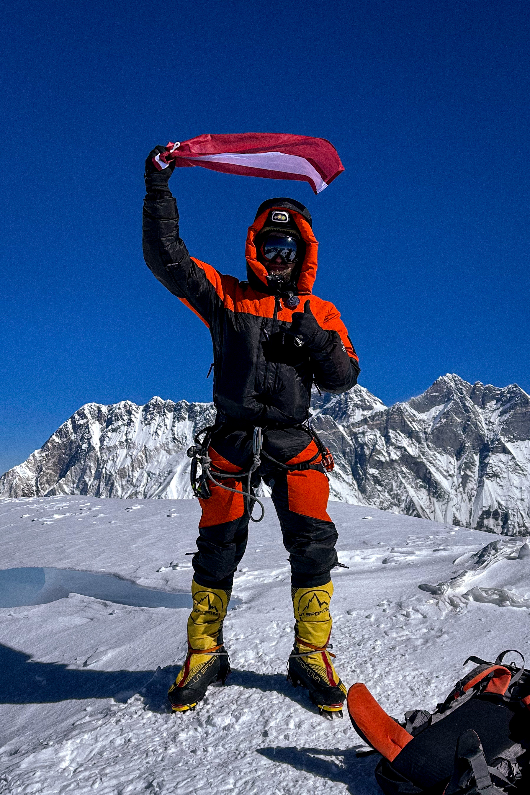 Alpīnists ar karogu virsotnē